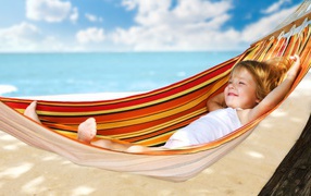 Маленькая улыбающаяся девочка в гамаке на пляже
