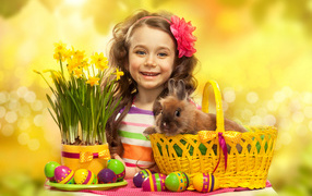Little smiling girl with a rabbit and painted eggs