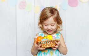 Маленькая улыбающаяся девочка с пасхальными яйцами в руках