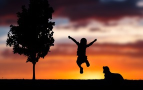 Silhouette of little boy with dog on sunset background