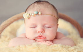 Спящая грудная девочка с красивым украшением на голове