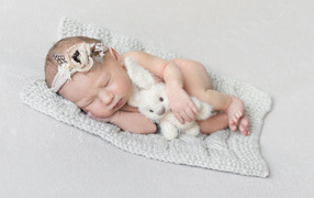 Спящий младенец с игрушкой на сером фоне 