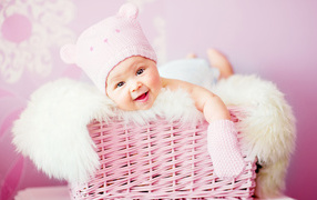 Smiling baby lies in a pink basket