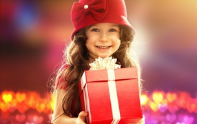 Улыбающаяся голубоглазая девочка с большим подарком в руках
