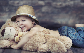 Smiling boy is hugging a toy