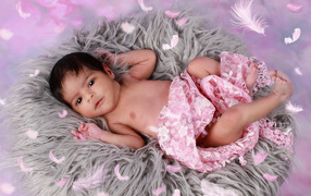 Младенец лежит на сером меховом покрывале 