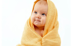 Грудной ребенок в желтом полотенце на белом фоне