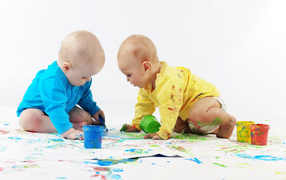 Два малыша рисуют красками на белом фоне