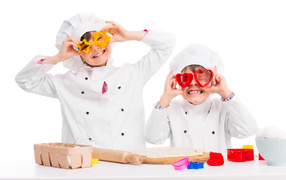 Two young children in chef costumes preparing cookies in the kitchen