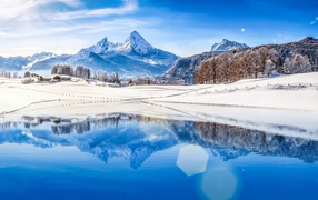 Заснеженные берега озера на фоне горы