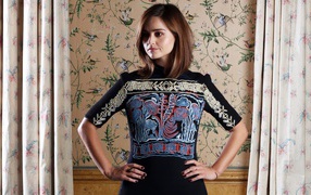 Actress Jenna Coleman in a beautiful dress against the wall