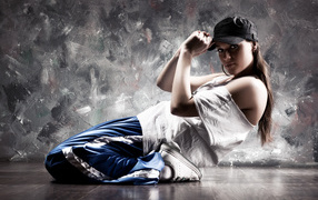 Girl dancer in a baseball cap and sports suit