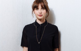 Popular actress Felicity Jones in a black shirt is standing by the wall
