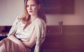 Молодая рыжеволосая актриса Джессика Честейн сидит на стуле