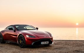 Red car 2018 Aston Martin Vantage on the background of the sunset near the water