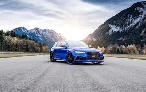 Синий автомобиль Audi RS 6 на фоне гор на дороге