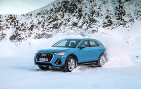 Голубой внедорожник Audi Q3, 2018 года на фоне заснеженных гор 