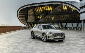 Серебристый автомобиль Audi E-Tron 55 Quattro 2019 года на фоне здания