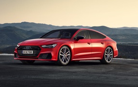 Красный автомобиль Audi A7 Sportback 55 TFSI E Quattro S Line 2019 года в горах