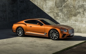 Orange car Bentley Continental GT V8, 2019 on the background of the wall