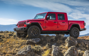 Red pickup truck Jeep Gladiator Rubicon on a hill with stones