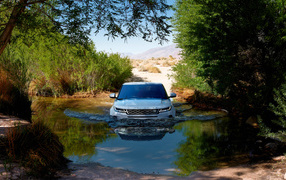 Белый внедорожник Range Rover Evoque едет по воде 