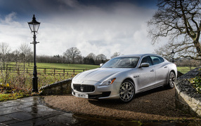 Silver stylish expensive car Maserati Quattroporte on the road after the rain