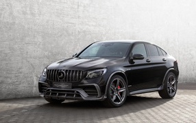 Черный автомобиль Mercedes-AMG GLC 63 на фоне серой стены 