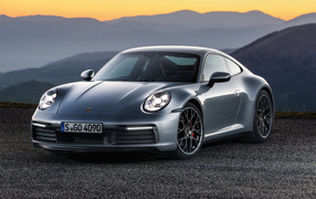Серебристый автомобиль Porsche 911 Carrera 4S 2019 года на фоне гор 