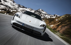 Белый автомобиль Porsche Taycan Turbo S 2019 года на фоне заснеженных гор