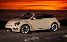 White Volkswagen Beetle SEL convertible in the background of the ocean at sunset