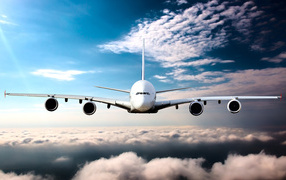 Самолет в белых облаках на фоне голубого неба