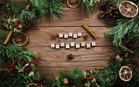 Merry Christmas lettering on a wooden table with fir branches.