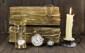 Старинные книги, зажженная свеча, ключи и часы на столе