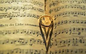 Золотое обручальное кольцо лежит на нотной тетради