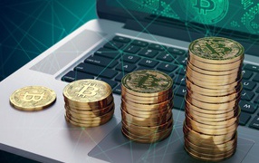 Золотые монеты Биткоин лежат на ноутбуке