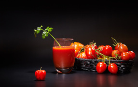 A glass of tomato juice on the table with tomatoes