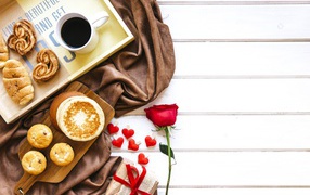 Выпечка на столе с кофе, подарком и красной розой