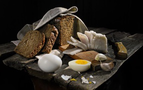 Black bread, boiled eggs, garlic and lard on a wooden table
