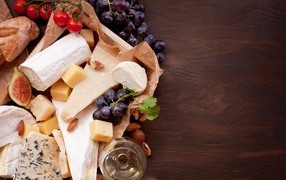 Сыр на столе с виноградом, инжиром и помидорами