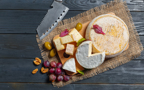 Сыр с плесенью на столе с орехами и виноградом 