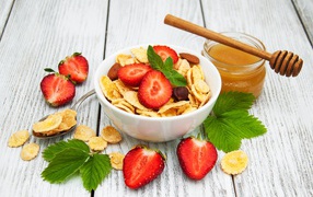 Cornflakes in a bowl with strawberries and honey