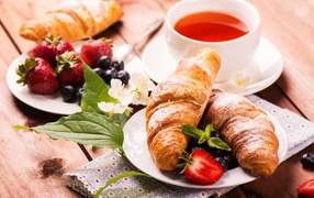 Croissants on a table with berries and a cup of tea