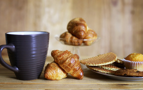 Cup on the table with croissants and waffles