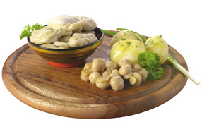 Dumplings with mushrooms and boiled potatoes on a wooden board on a white background
