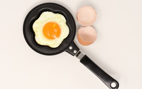 Fried eggs in a pan on a gray background with shell