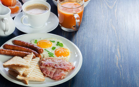 Fried eggs on a plate with sausages, bacon and croutons on a table with coffee and juice