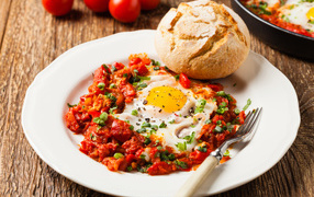 Яичница с овощами на белой тарелке с булкой 