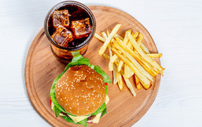 Hamburger on a board with fries and cola