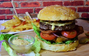 Hamburger with bacon on the table with sauce and french fries